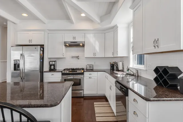 a kitchen with kitchen island granite countertop a sink stove refrigerator and cabinets