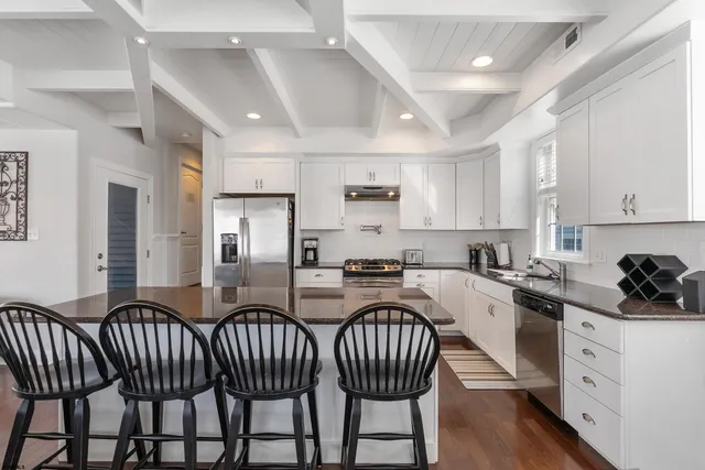 a kitchen with granite countertop a sink chairs and refrigerator