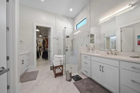 a spacious bathroom with a double vanity sink a large mirror and a shower