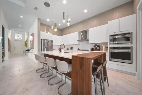 a kitchen with stainless steel appliances kitchen island granite countertop a table chairs and a refrigerator