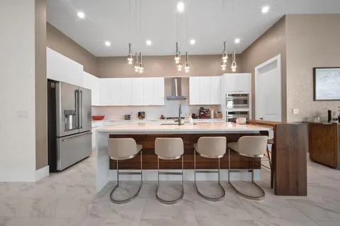 a kitchen with stainless steel appliances kitchen island granite countertop a table chairs sink and cabinets