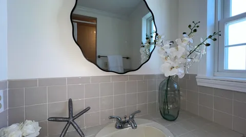 a bathroom with a sink and mirror with bathtub