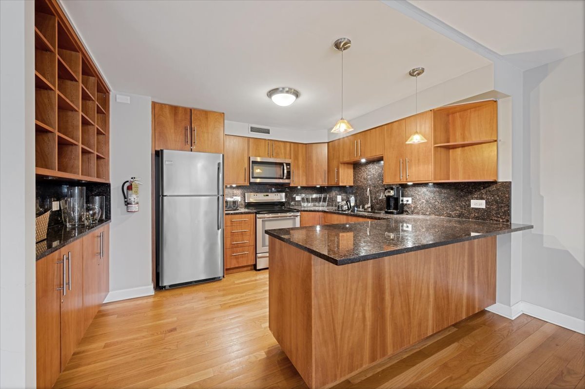 5855 North Sheridan Road, Unit 25G Chicago, IL 60660 - Photo 27 of 29 a kitchen with stainless steel appliances granite countertop a refrigerator a sink a stove a microwave and island