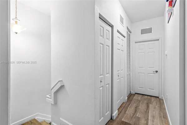 a view of a hallway with wooden floor and closet area
