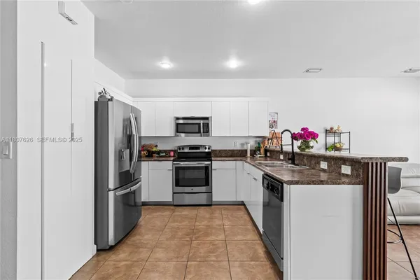 a kitchen with stainless steel appliances granite countertop a refrigerator a stove and a sink