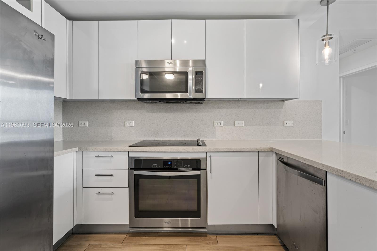 999 Southwest 1st Avenue, Unit 2411 Miami, FL 33130 - Photo 4 of 72 a kitchen with white cabinets and stainless steel appliances