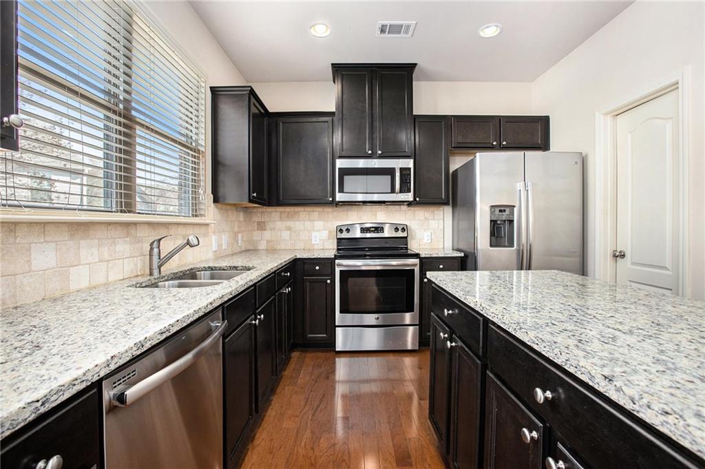 2426 Bellyard Drive Buford, GA 30519 - Photo 11 of 25 a kitchen with stainless steel appliances granite countertop a sink stove and refrigerator