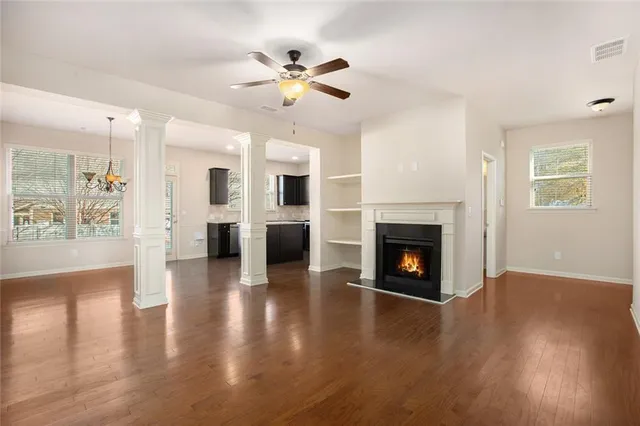a view of a livingroom with a fireplace a ceiling fan and a kitchen view