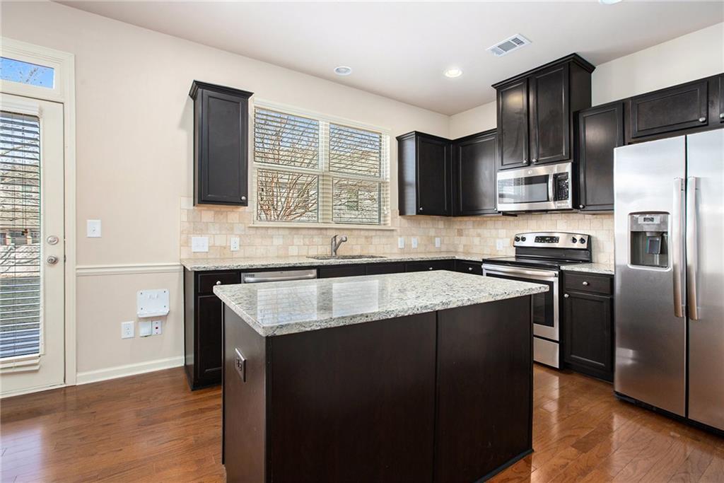 2426 Bellyard Drive Buford, GA 30519 - Photo 10 of 25 a kitchen with kitchen island granite countertop stainless steel appliances a sink stove refrigerator and a window