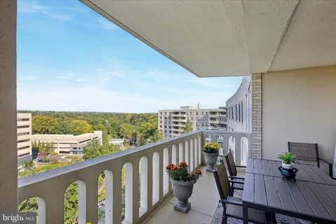 a view of a balcony with wooden chairs and floor to ceiling window