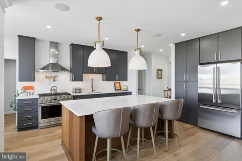 a kitchen with stainless steel appliances a dining table chairs stove and refrigerator