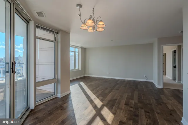 an empty room with wooden floor mirror and windows