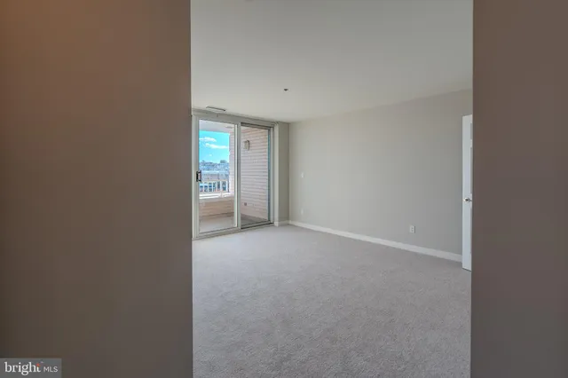 a view of an empty room with closet and a window