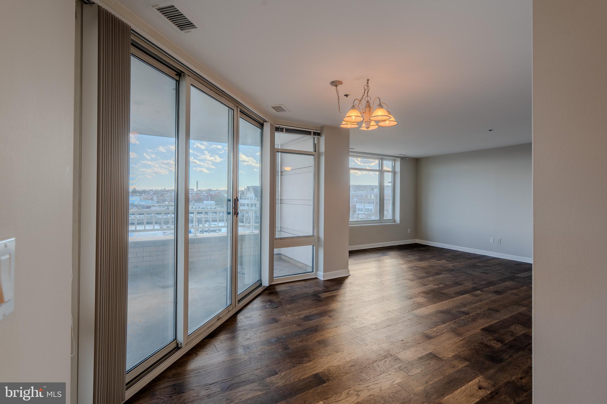 100 Harborview Drive, Unit 302 Baltimore, MD 21230 - Photo 10 of 48 an empty room with wooden floor and windows