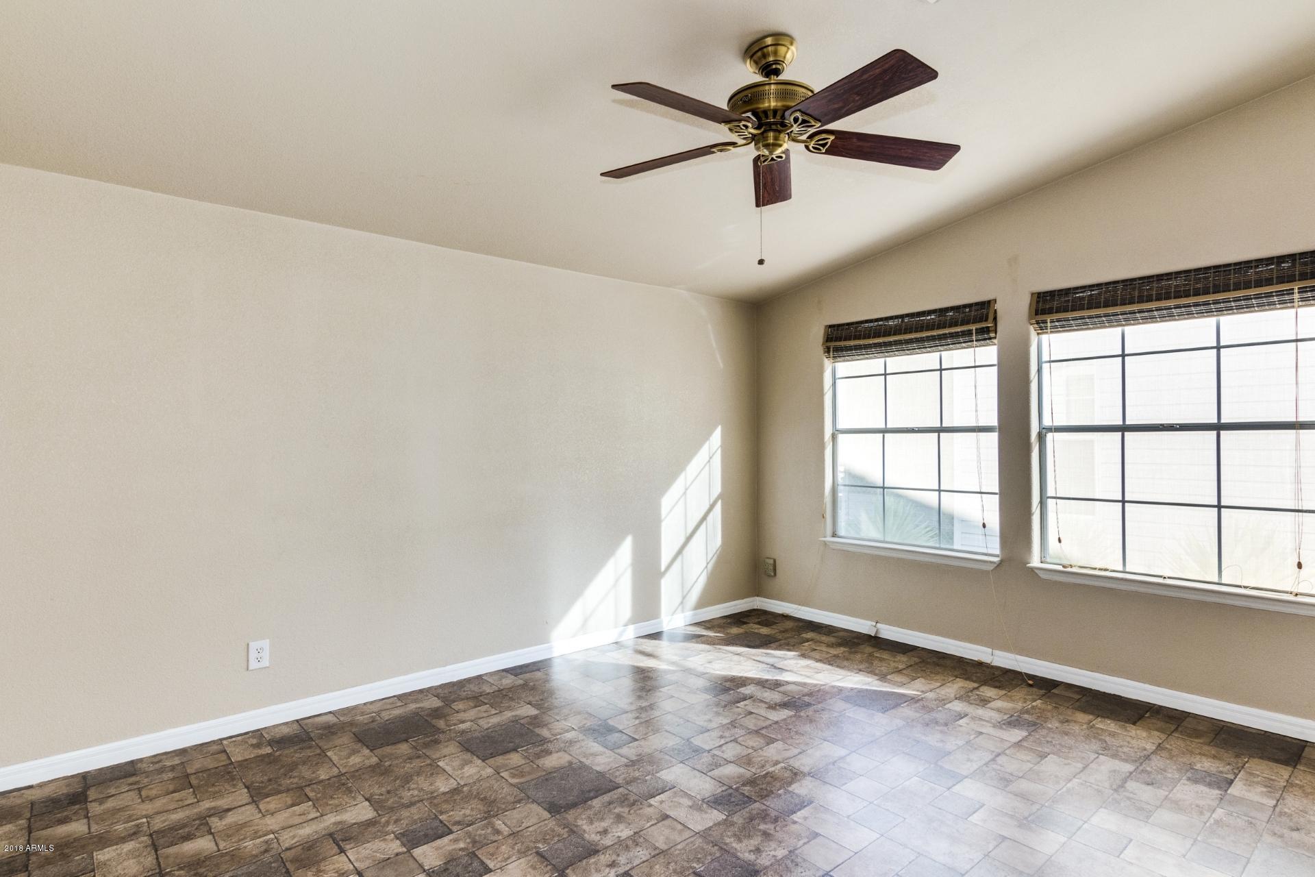 3301 South Goldfield Road, Unit 2041 Apache Junction, AZ 85119 - Photo 7 of 26 an empty room with chandelier fan and windows