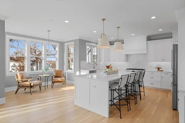 a kitchen with stainless steel appliances kitchen island granite countertop a dining table chairs and white cabinets