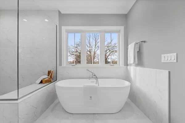 a white bath tub sitting in a bathroom next to a window