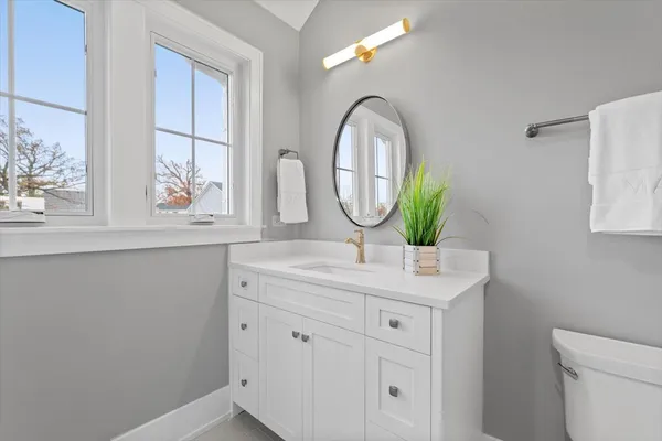a bathroom with a granite countertop toilet a sink and mirror