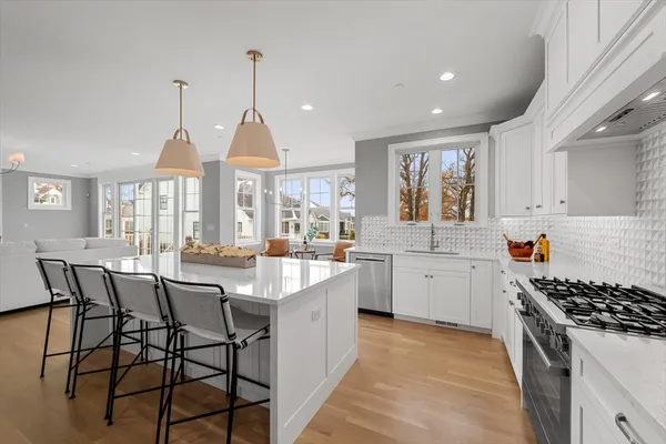 a kitchen with stainless steel appliances a stove a sink a center island and windows