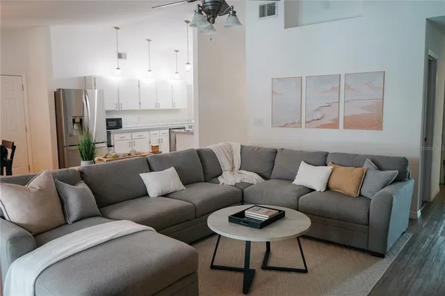 a living room with furniture a refrigerator and a chandelier