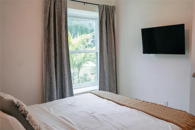 a bedroom with a bed and a flat tv screen on dresser