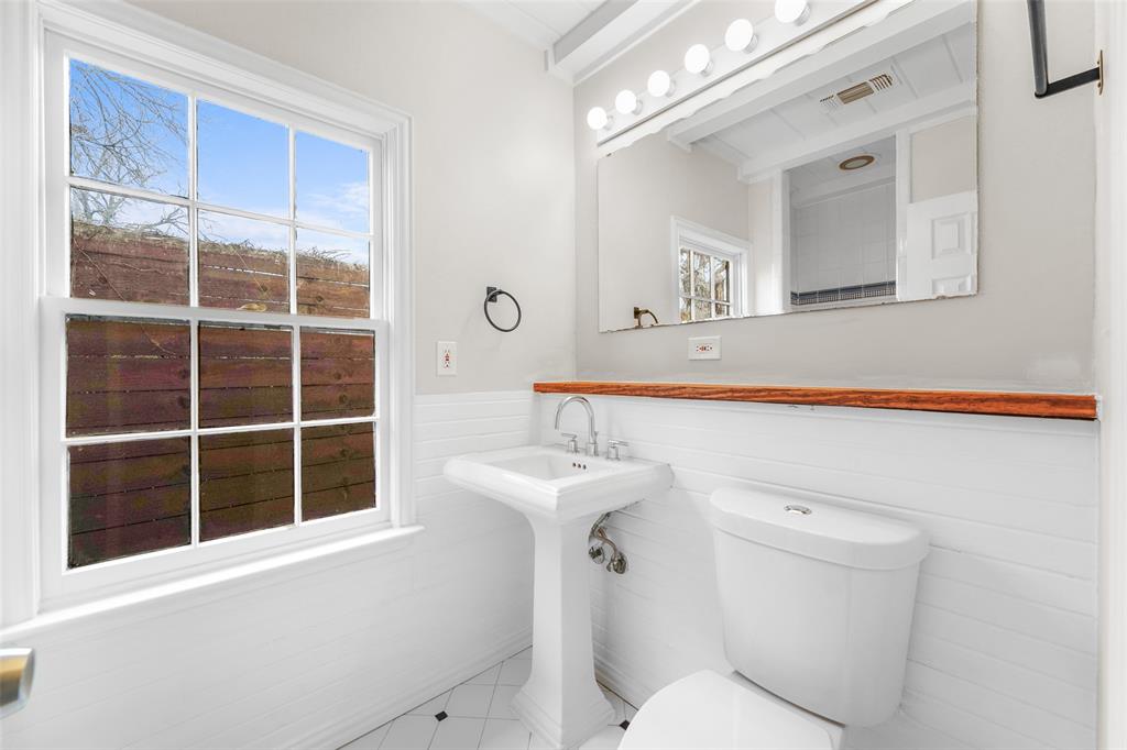311 North Tennant Street Dallas, TX 75208 - Photo 21 of 23 a bathroom with a sink a mirror a toilet and a window