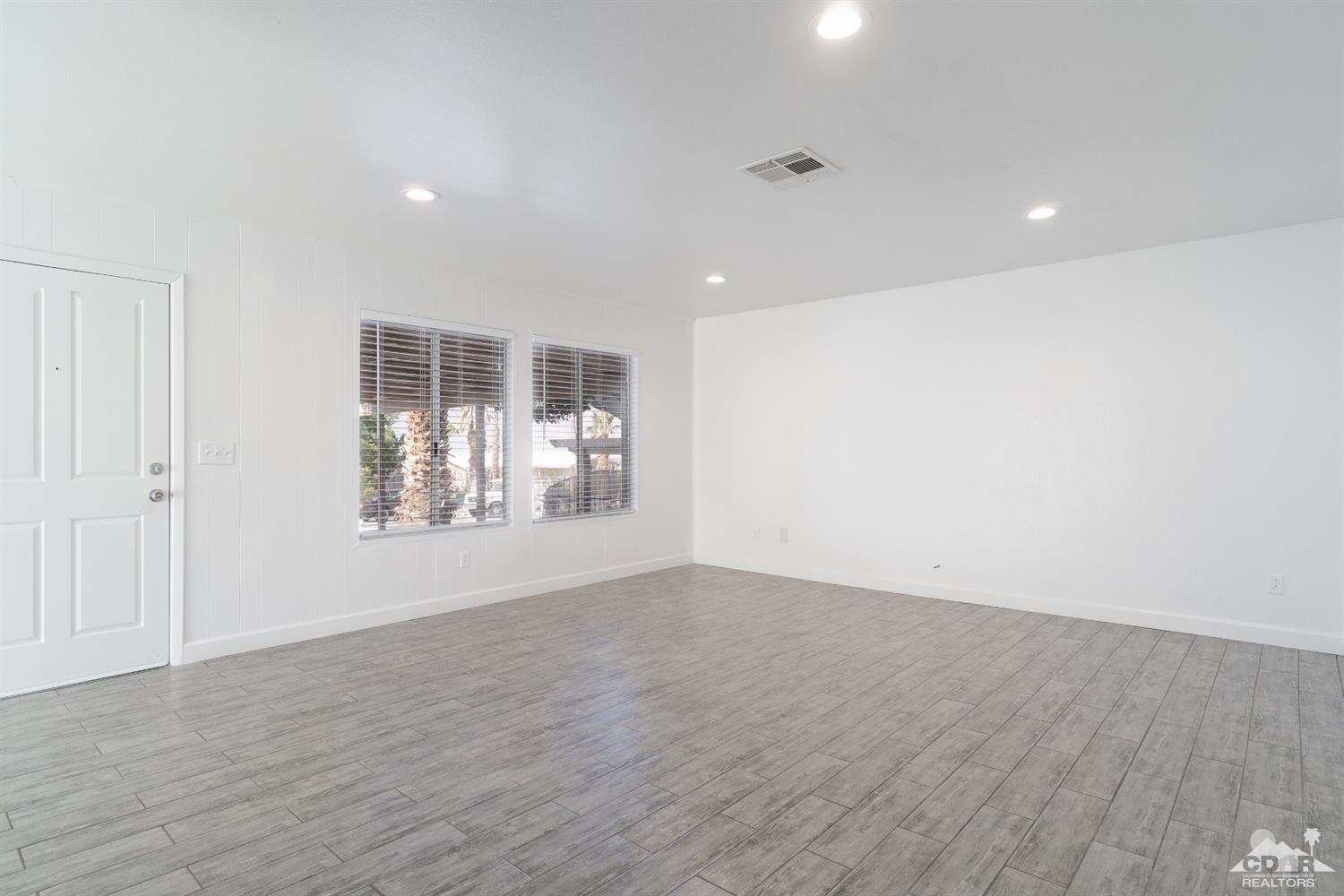 66186 Santa Rosa Road Desert Hot Springs, CA 92240 - Photo 19 of 23 an empty room with wooden floor and windows