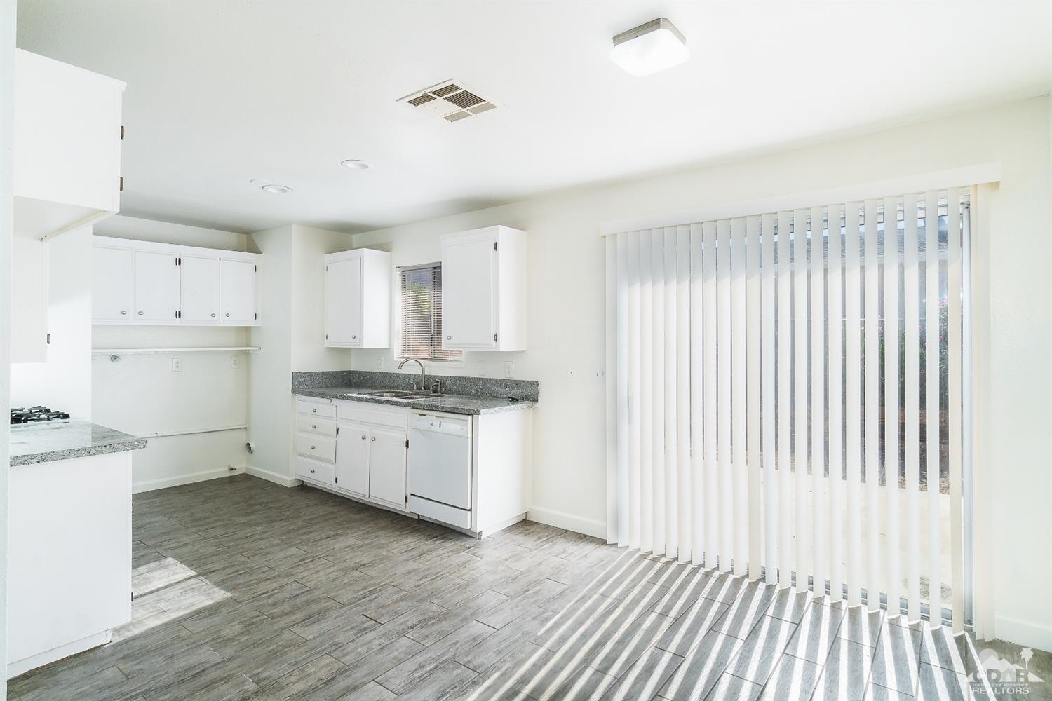 66186 Santa Rosa Road Desert Hot Springs, CA 92240 - Photo 4 of 23 a kitchen with a refrigerator oven stove cabinets and wooden floor