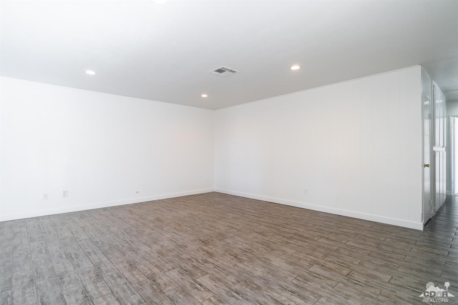 66186 Santa Rosa Road Desert Hot Springs, CA 92240 - Photo 5 of 23 an empty room with wooden floor and white walls