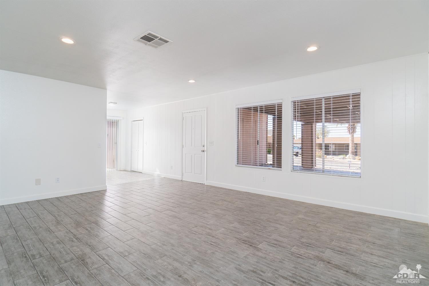66186 Santa Rosa Road Desert Hot Springs, CA 92240 - Photo 6 of 23 a view of an empty room with wooden floor and a window