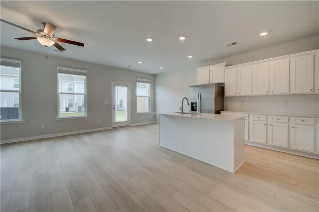 a kitchen with stainless steel appliances a sink a stove a refrigerator cabinets and a window