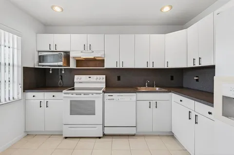 a kitchen with white cabinets and white appliances