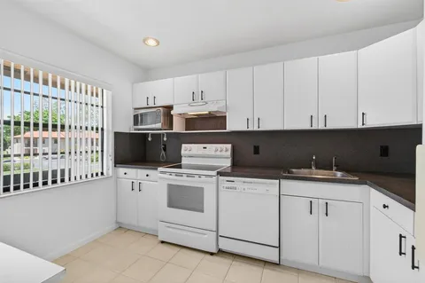 a kitchen with granite countertop white cabinets and white appliances
