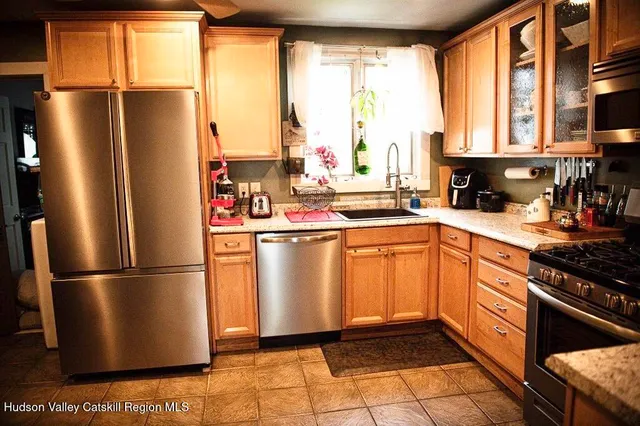 a kitchen with stainless steel appliances granite countertop a refrigerator a sink dishwasher a stove and a refrigerator