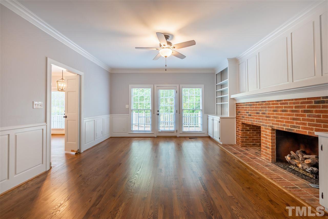 2408 Heartley Drive Raleigh, NC 27615 - Photo 4 of 26 an empty room with wooden floor fireplace and windows
