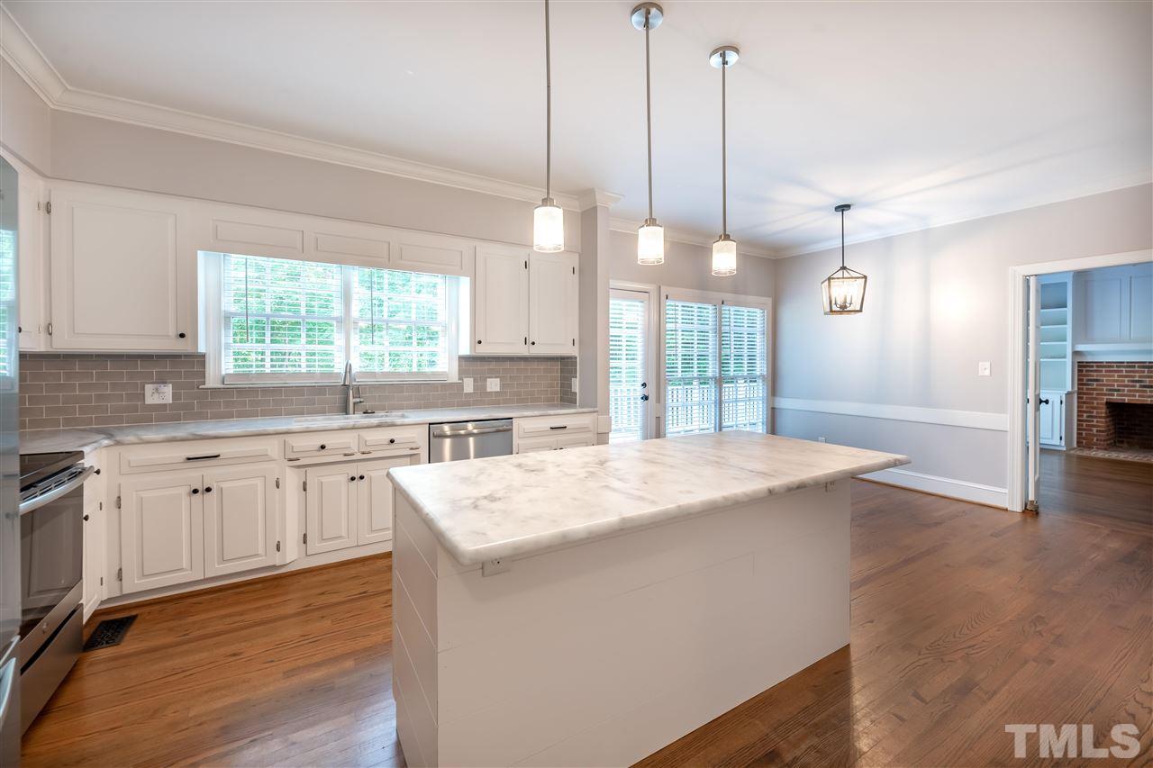 2408 Heartley Drive Raleigh, NC 27615 - Photo 8 of 26 a large kitchen with kitchen island a stove a sink a center island and wooden floor