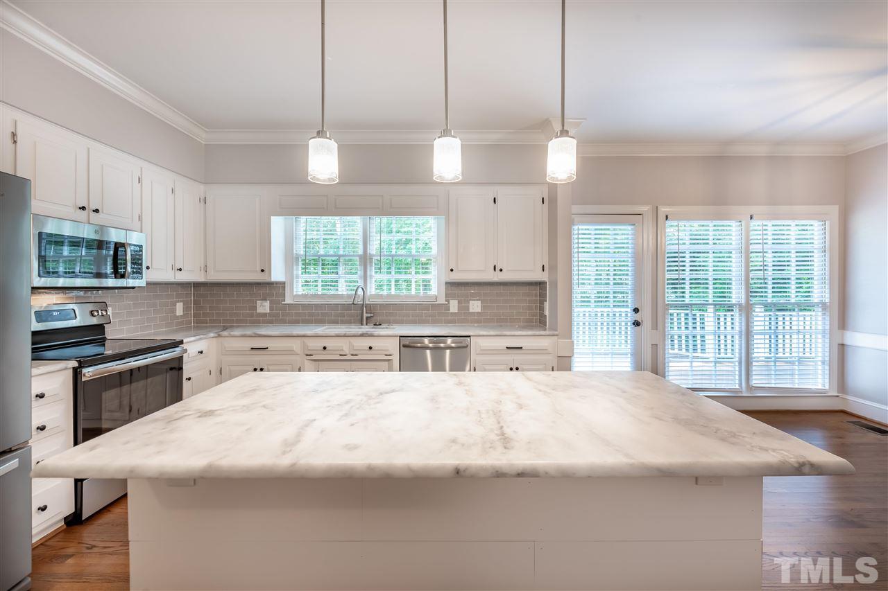 2408 Heartley Drive Raleigh, NC 27615 - Photo 9 of 26 a large kitchen with kitchen island a large counter space a sink appliances and cabinets