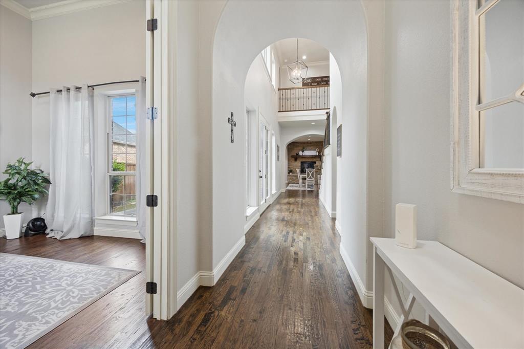 580 Butchart Drive Prosper, TX 75078 - Photo 14 of 40 Corridor featuring arched walkways, ornamental molding, dark wood-style flooring, baseboards, and a towering ceiling