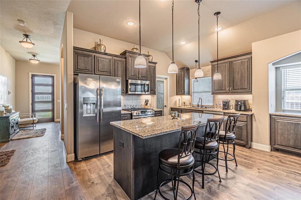 4201 Misty Ridge Street Mesquite, TX 75181 - Photo 11 of 39 Kitchen featuring a center island, light stone counters, decorative light fixtures, decorative backsplash, and appliances with stainless steel finishes