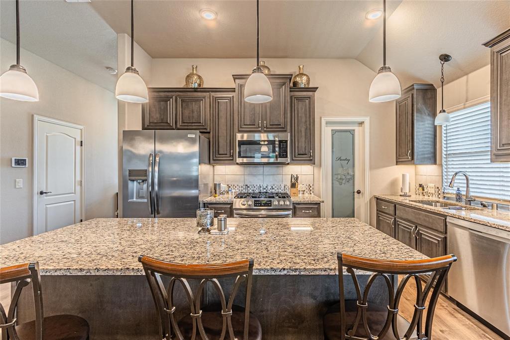 4201 Misty Ridge Street Mesquite, TX 75181 - Photo 12 of 39 Kitchen with sink, a center island, pendant lighting, dark brown cabinets, and appliances with stainless steel finishes