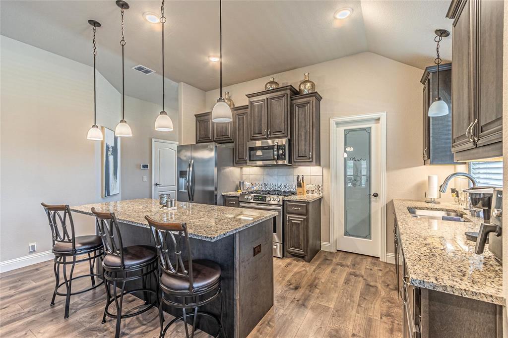 4201 Misty Ridge Street Mesquite, TX 75181 - Photo 13 of 39 Kitchen with sink, stainless steel appliances, light stone counters, lofted ceiling, and a kitchen island