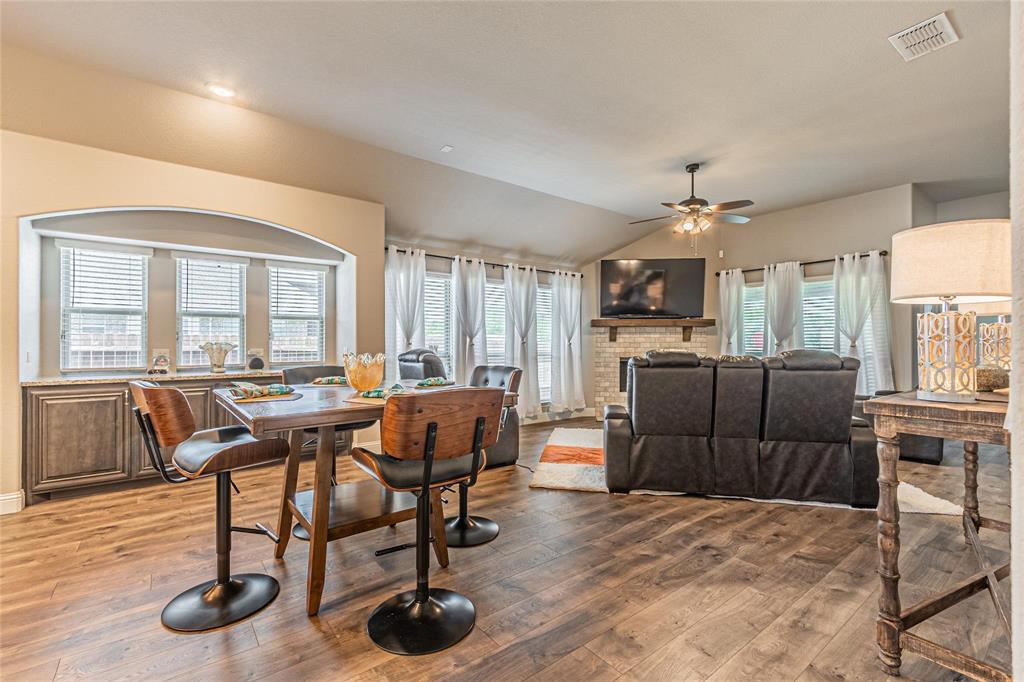 4201 Misty Ridge Street Mesquite, TX 75181 - Photo 16 of 39 Dining area featuring hardwood / wood-style floors, vaulted ceiling, a brick fireplace, and a healthy amount of sunlight