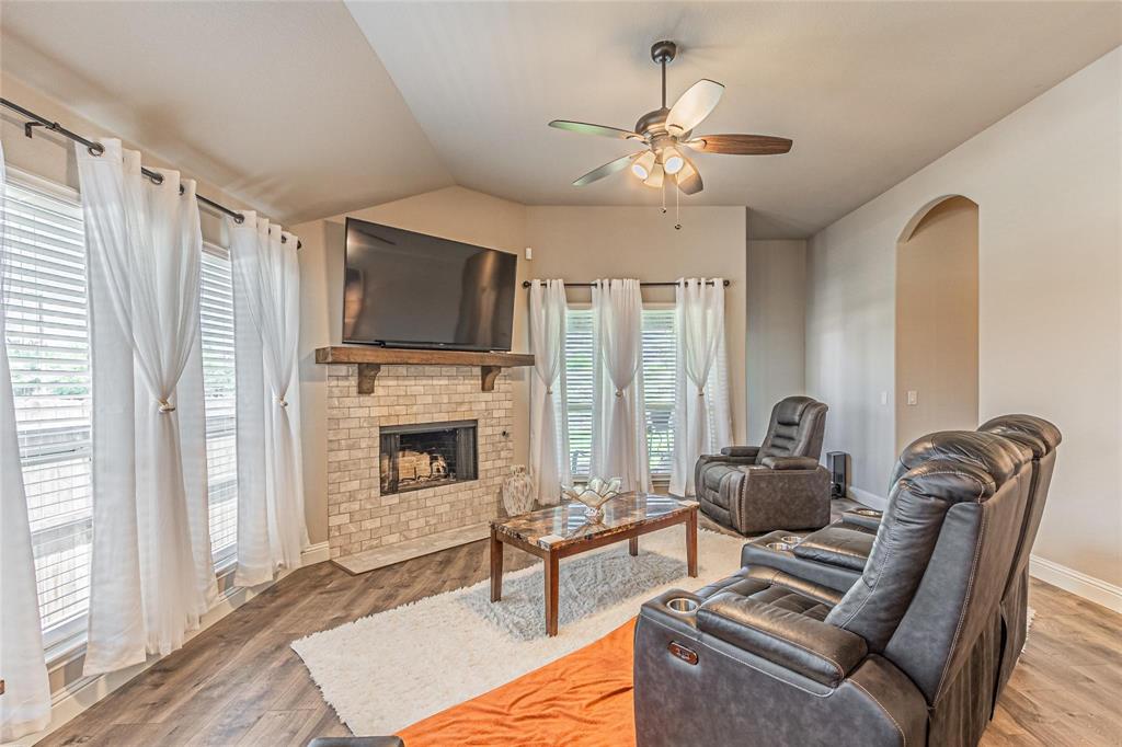 4201 Misty Ridge Street Mesquite, TX 75181 - Photo 18 of 39 Living room featuring ceiling fan, vaulted ceiling, wood-type flooring, and a brick fireplace