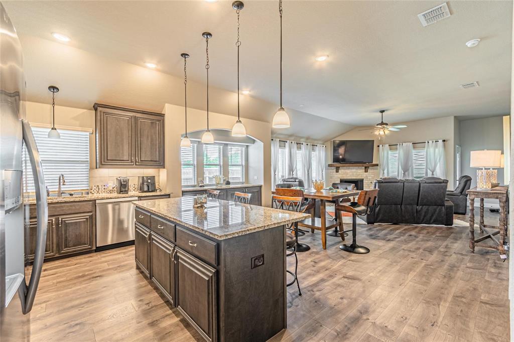 4201 Misty Ridge Street Mesquite, TX 75181 - Photo 9 of 39 Kitchen with a center island, hanging light fixtures, light stone counters, lofted ceiling, and appliances with stainless steel finishes