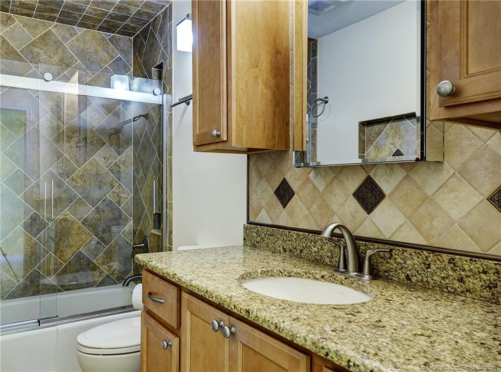 5290 Southeast Seascape Way, Unit 201 Stuart, FL 34997 - Photo 13 of 30 a bathroom with a granite countertop sink and a mirror