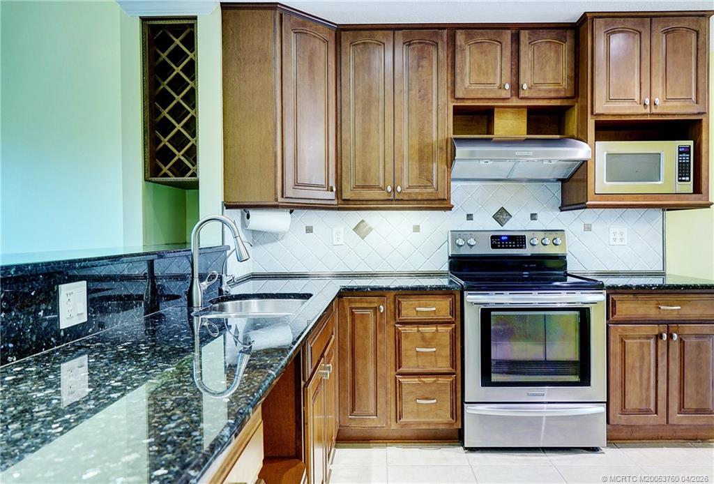 5290 Southeast Seascape Way, Unit 201 Stuart, FL 34997 - Photo 5 of 30 a kitchen with wooden cabinets and a stove top oven