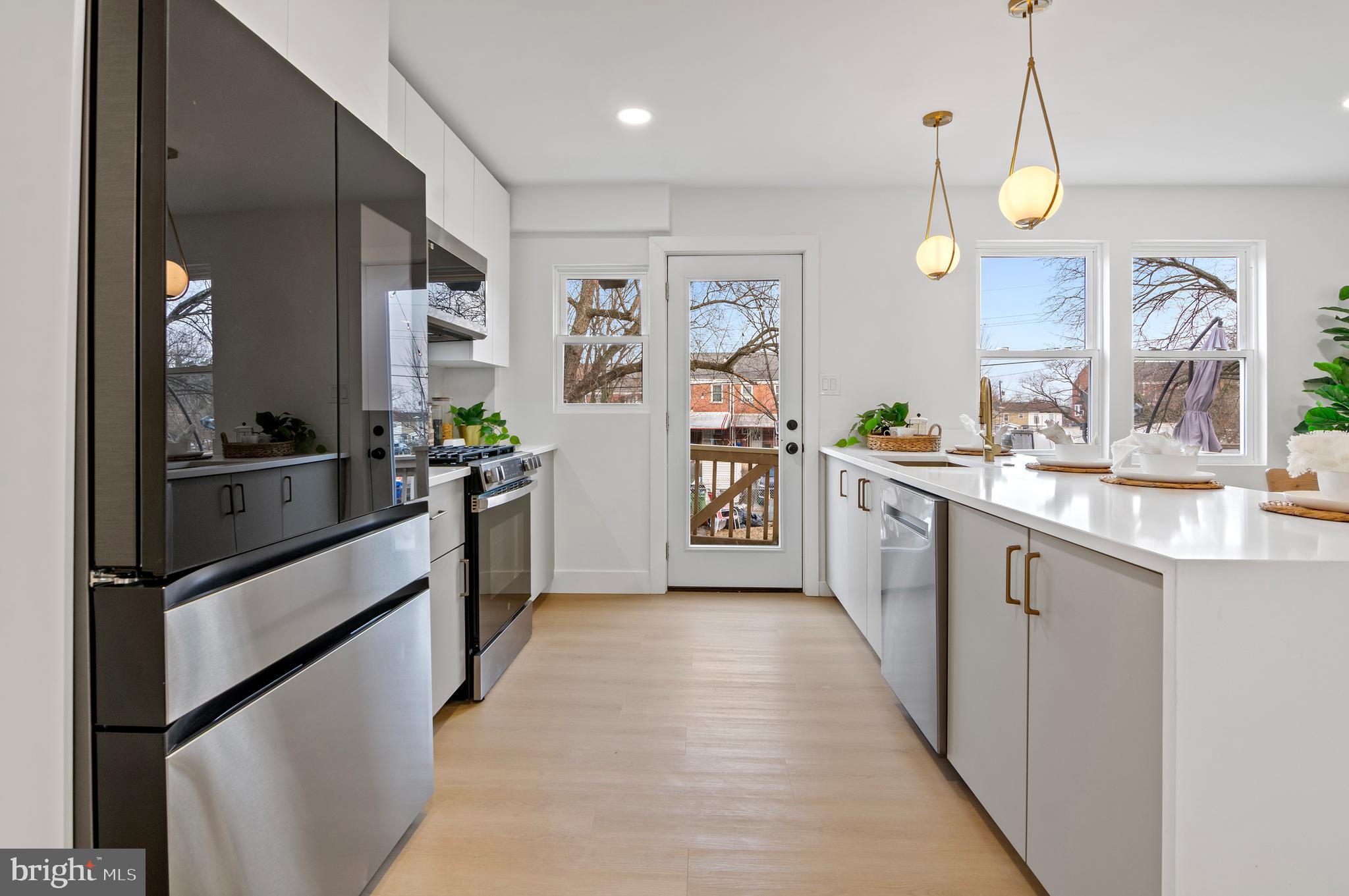 5905 Glenkirk Road Baltimore, MD 21239 - Photo 11 of 31 a large kitchen with stainless steel appliances kitchen island granite countertop a sink and cabinets