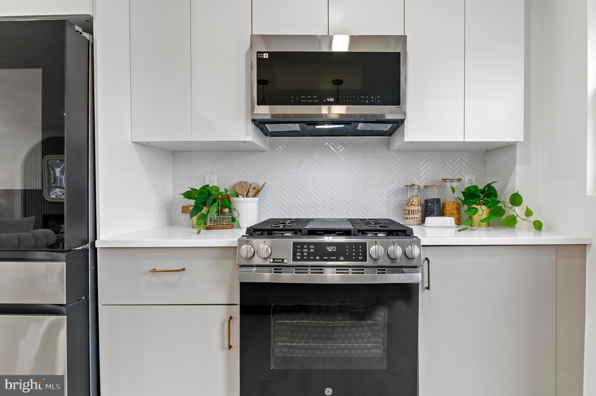 5905 Glenkirk Road Baltimore, MD 21239 - Photo 12 of 31 a kitchen with stainless steel appliances granite countertop a stove a microwave and cabinets