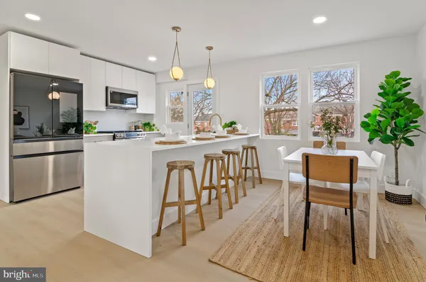 a kitchen with stainless steel appliances a dining table chairs and a refrigerator