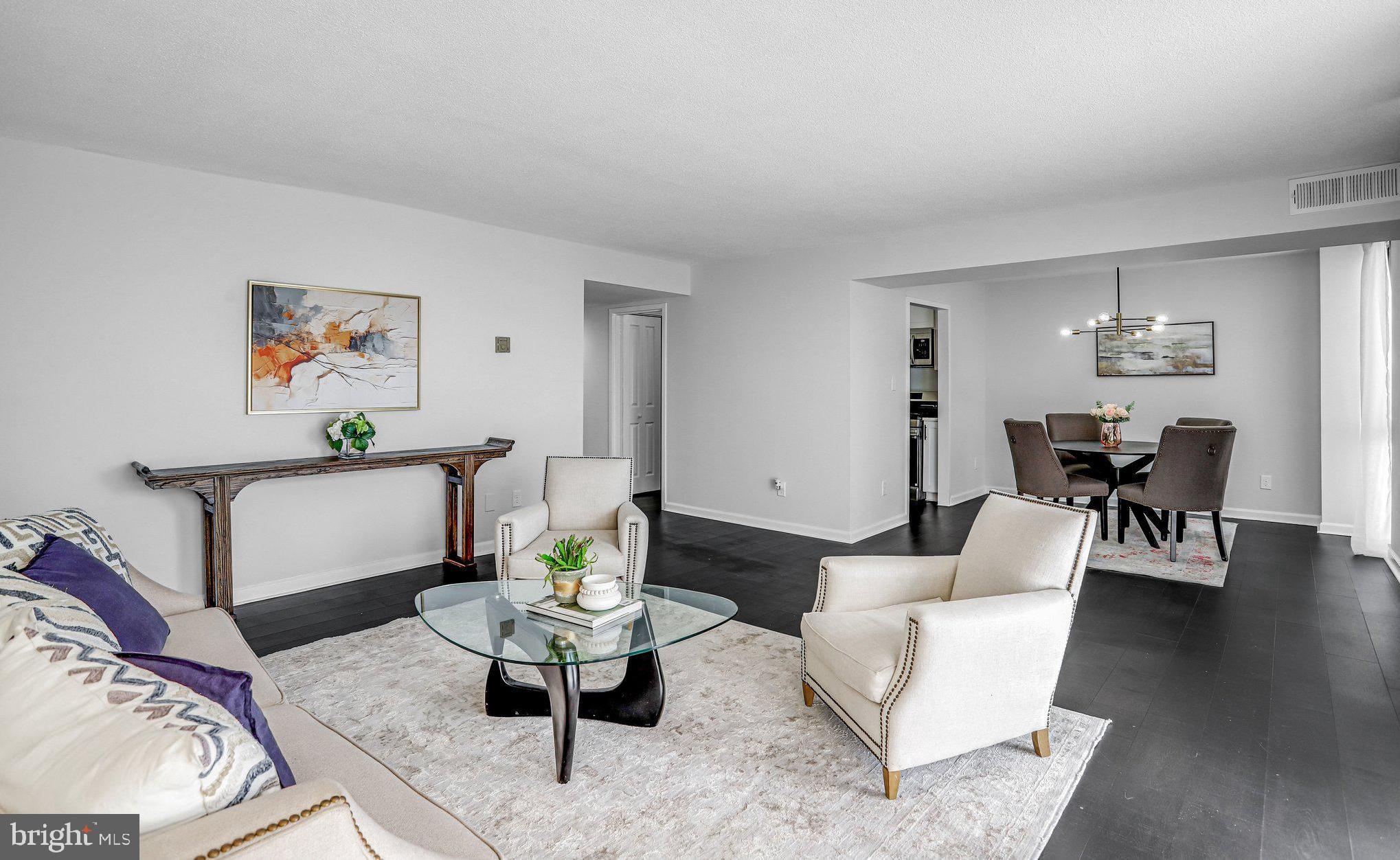 a living room with furniture and a dining table with wooden floor